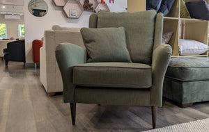 Green armchair with cushions in a showroom setting