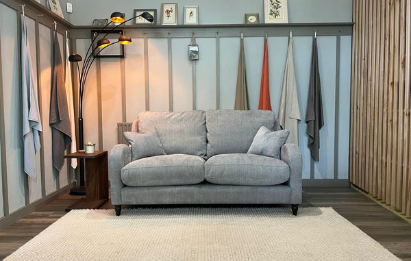 Gray sofa in a room with wooden flooring and striped walls.