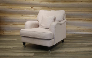 Light pink armchair with a pillow against a wooden paneled wall.