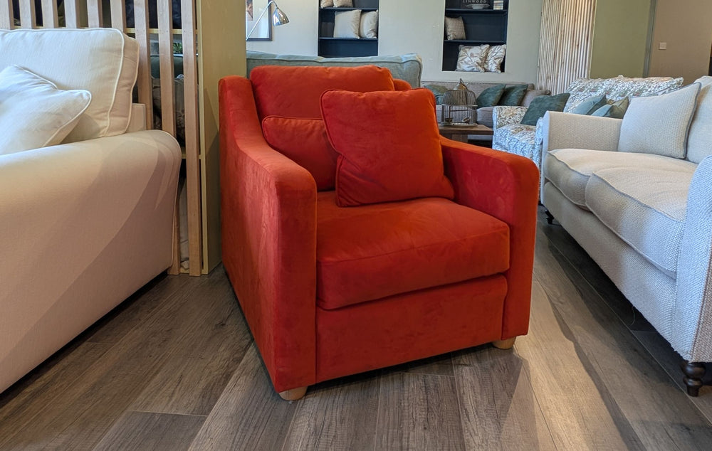 Orange armchair in a showroom with beige and gray sofas.
