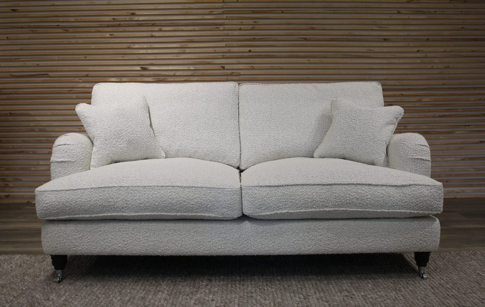 White boucle sofa with cushions against a wooden paneled wall.